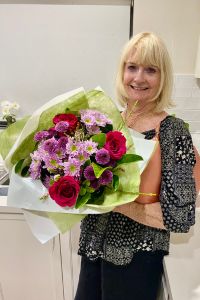Keryl at home holding a colourful bouquet of flowers.