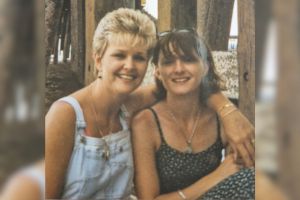 An old photograph of Leslie and Jackie sitting together, with Leslie's arm around Jackie's shoulders.