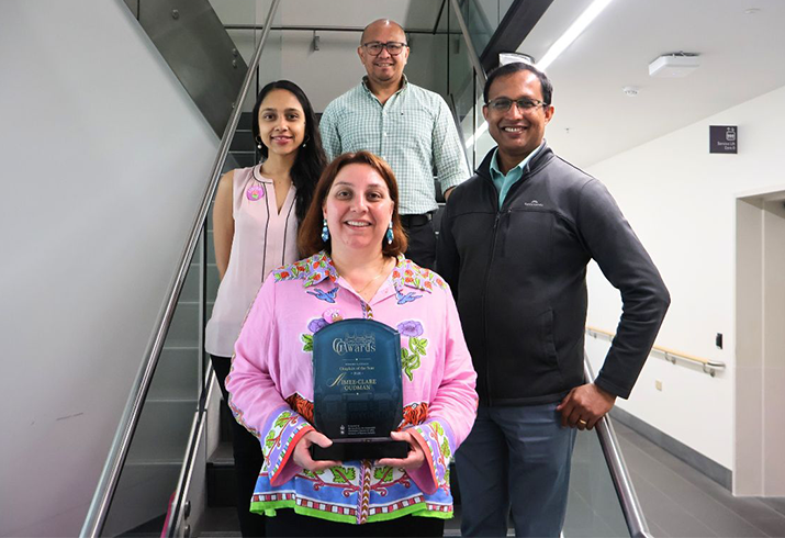 Clare Oudman pictured front and centre holding her award wearing a bright pink top, accompanied by her pastoral care team standing either side and behind her. 