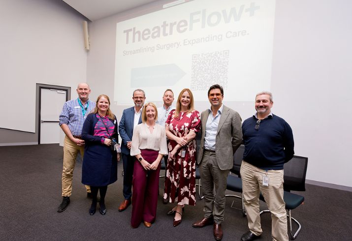 Staff involved in the project standing together in front of a presentations screen. 