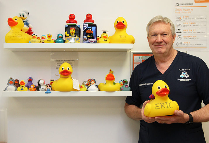 Eric Watson pictured standing next to a wall of yellow rubber ducks that have been collected over the years. 