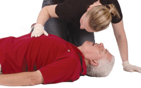 Woman placing her hand on a patient&rsquo;s chest and placing her cheek over man&rsquo;s mouth to check for signs of man breathing.