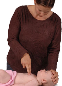 Woman placing two fingers on an infant&rsquo;s chest and pushing down to perform chest compressions.